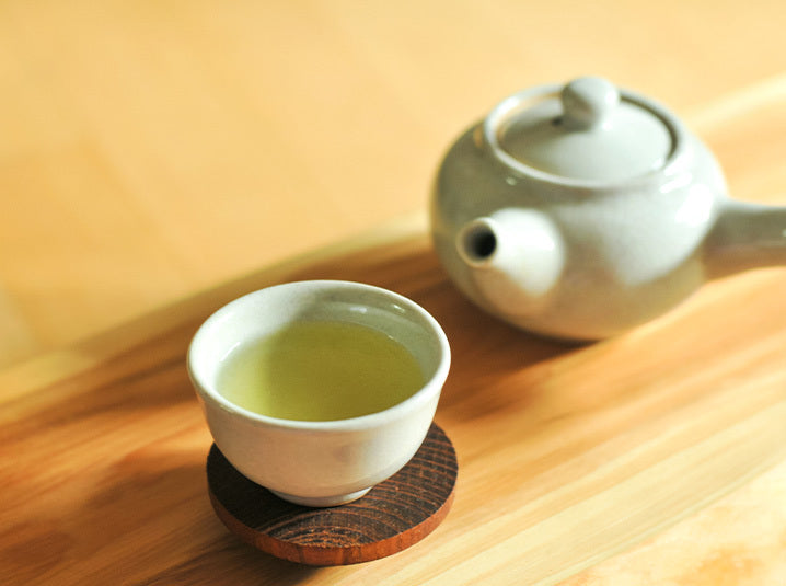 Brewed Green Tea in a white ceramic cup with white teapot beside