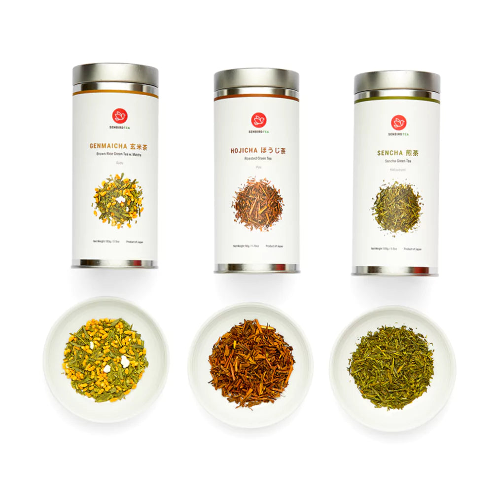 Senbird Japanese Green Tea Gift Set contents showing Sencha Hatsuzumi Genmaicha Suzu Hojicha Yuu tins and loose leaf tea on white dishes
