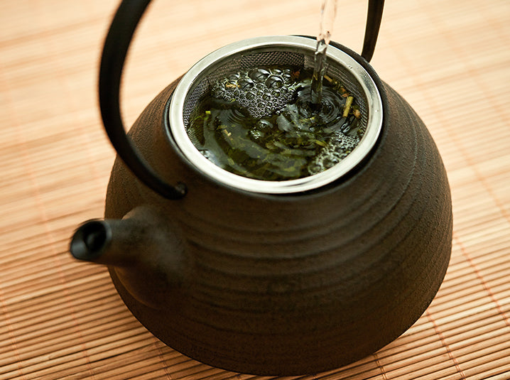 Pouring water in black teapot