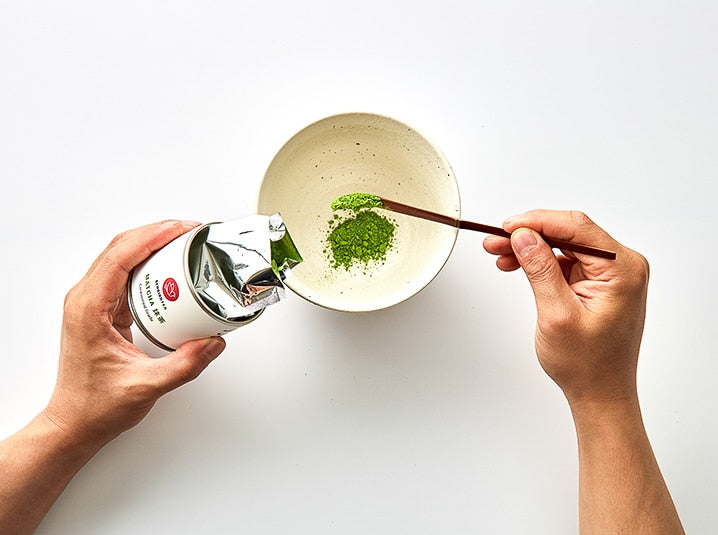 putting matcha green tea powder in a plate through tea scoop