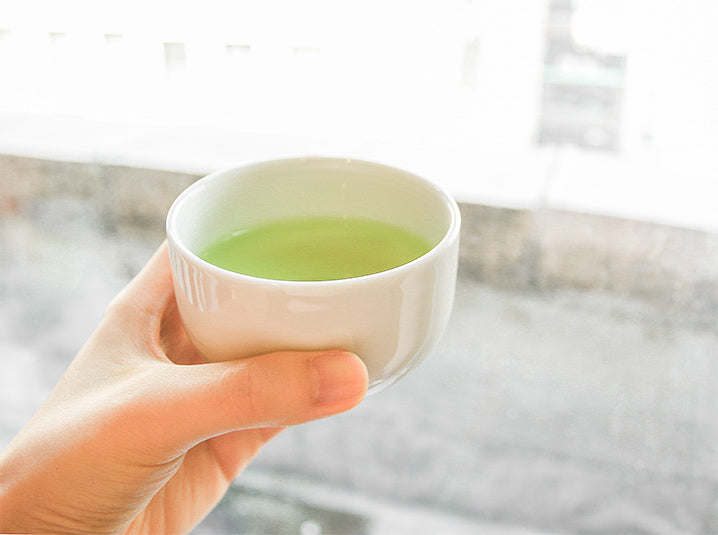 hand holding a cup full of brewed tea