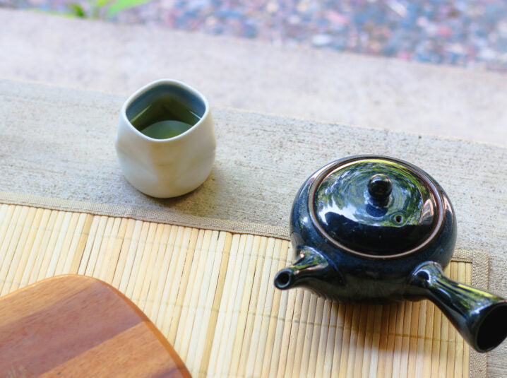 black kyusu with a glass filled with tea