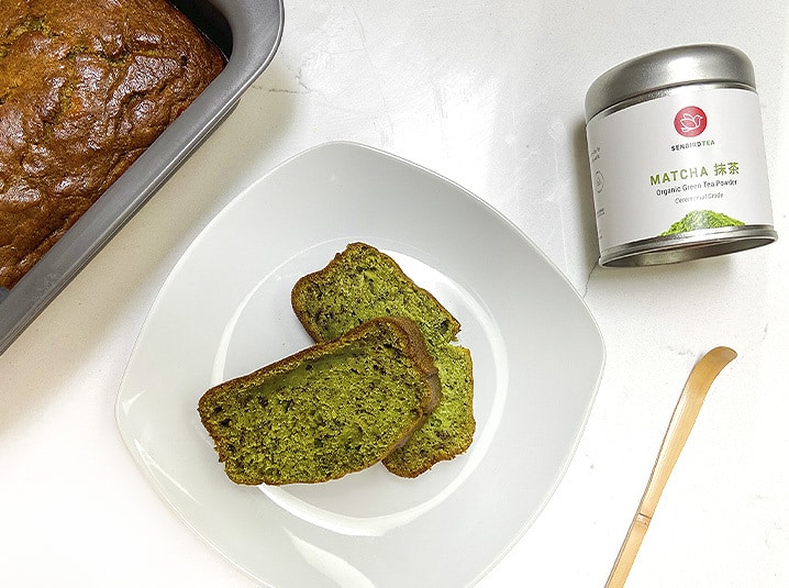 2 slices of Matcha Banana Bread in a plate with matcha tea tin and tea scoop