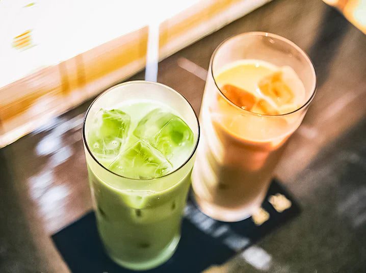 Iced matcha latte beside iced hojicha latte for comparing Japanese green tea drinks