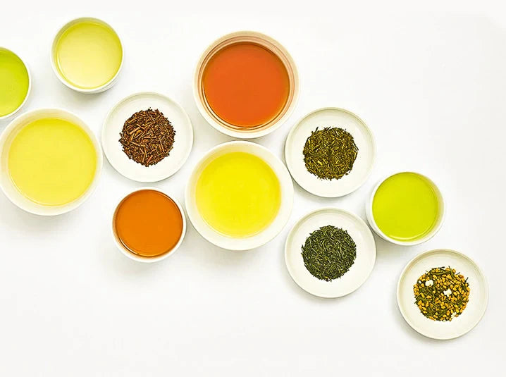 Overhead flat lay of brewed Japanese teas and loose leaf teas including sencha, hojicha, and genmaicha