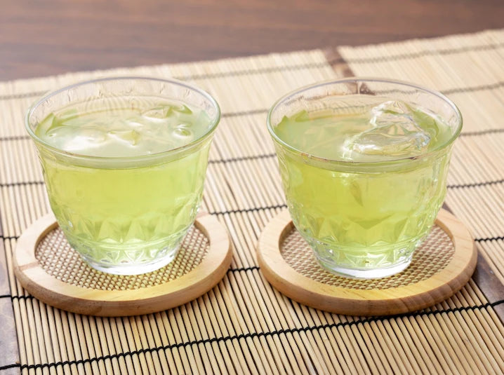 Japanese sencha green tea leaves in a traditional setting with a cup of brewed pale green sencha