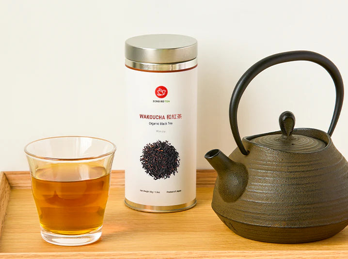 Senbird Wakoucha Japanese black tea tin with glass cup and tetsubin teapot on a natural wood tray