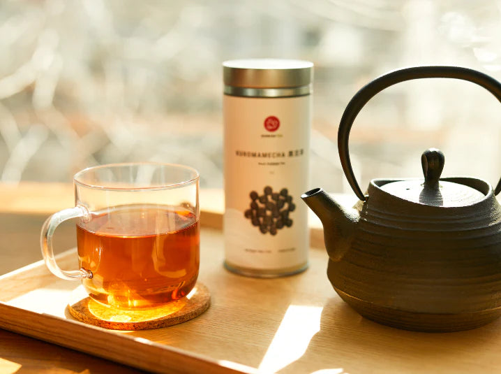 A cozy mug of kuromamecha black soybean herbal tea with a tetsubin cast-iron teapot in a warm fall setting