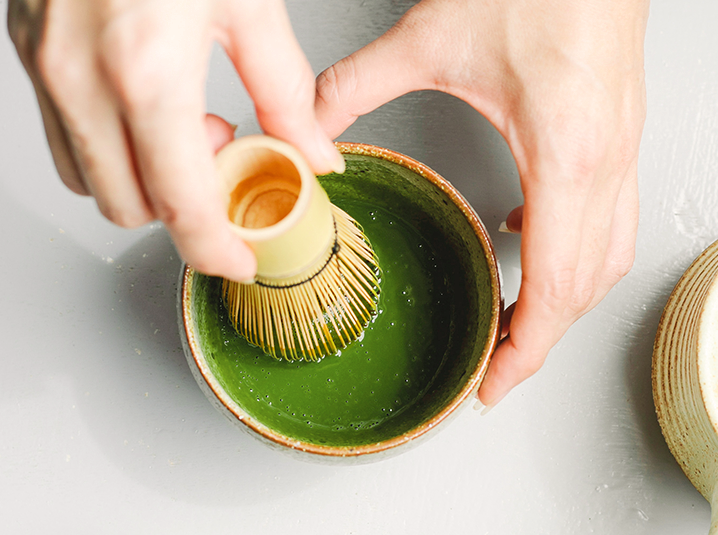 hands whisking matcha in a cup