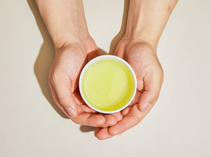 Warm sencha or gyokuro shade-grown green tea cup held in hands