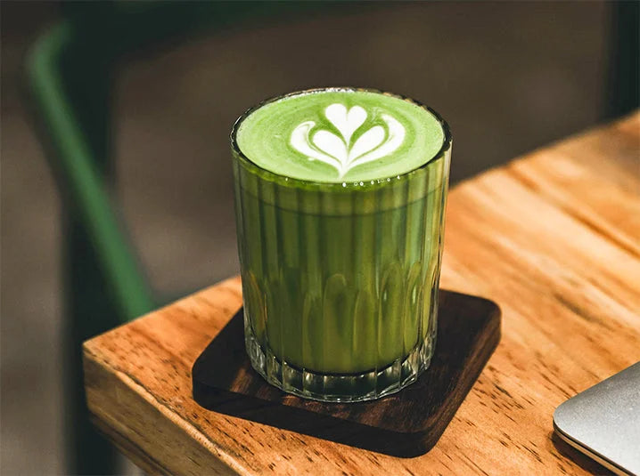 Foamy hot matcha green tea latte served in a clear glass cup