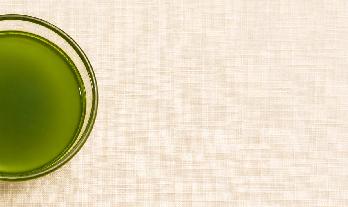 Glass of prepared Aojiru Japanese green juice on beige linen