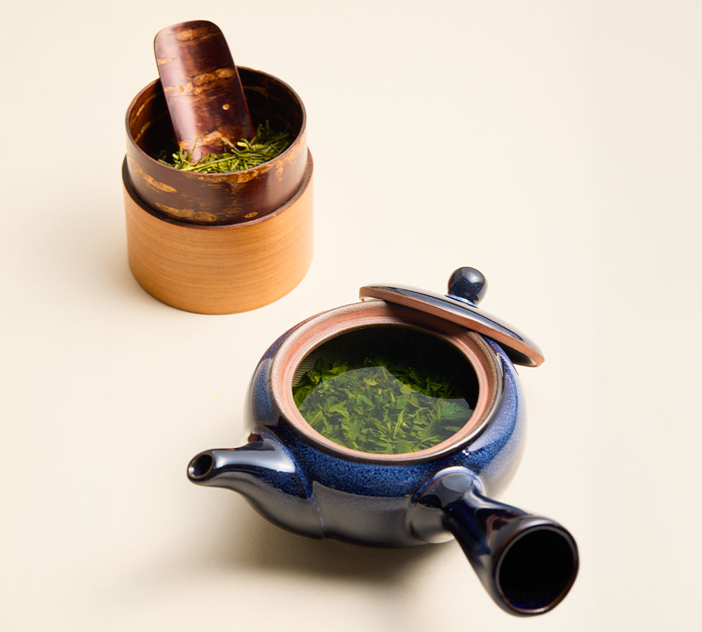 Wooden Japanese green tea canister with Sencha leaves and blue kyusu teapot
